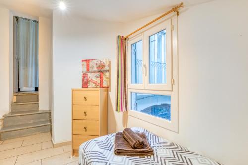 - une chambre avec un lit, une commode et des fenêtres dans l'établissement Appartement La Lumineuse, à Béziers