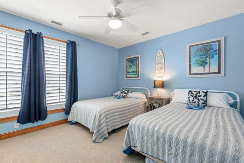 a bedroom with two beds and blue walls at Slip 111 in Manteo