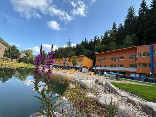 a building next to a body of water with purple flowers at Resort Špindl in Špindlerův Mlýn