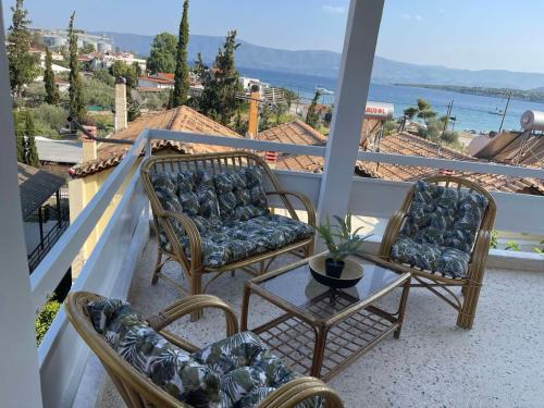 three chairs and a table on a balcony with a view at Maison De La Mer in Isthmia