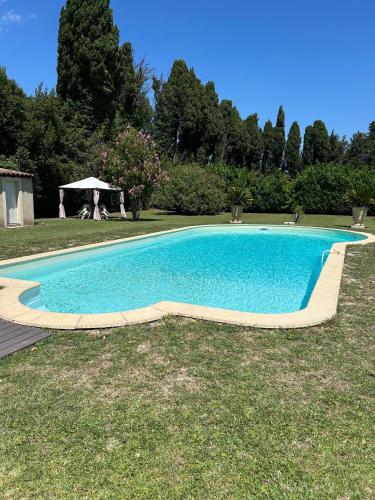 a swimming pool in the grass with a gazebo at Studio tout confort avec terrasse et piscine, idéal pour un séjour relax in Cabannes