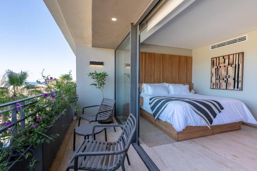 a bedroom with a bed and two chairs on a balcony at Punto Nima, Spectacular Pool with Ocean View in San José del Cabo