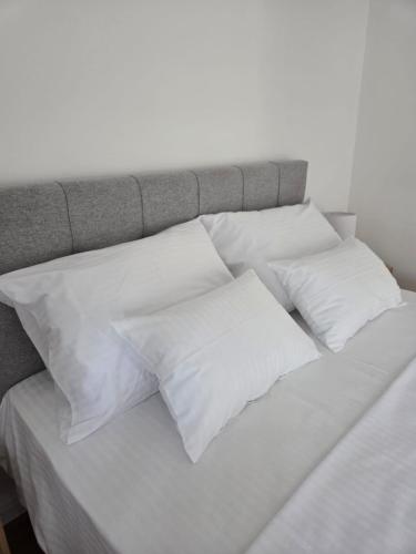 a bed with four white pillows on it at Apartmani Novak in Mostar