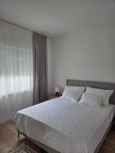 a bedroom with a large bed with white sheets at Apartmani Novak in Mostar