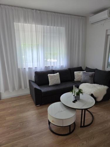 a living room with a black couch and a table at Apartmani Novak in Mostar