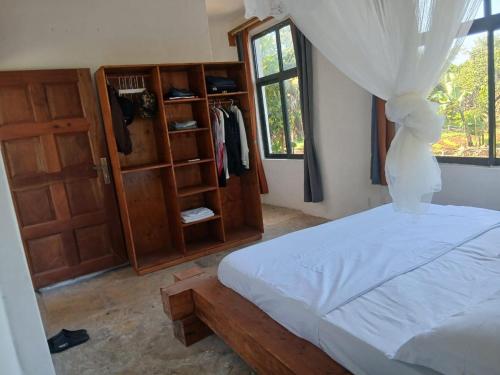 a bedroom with a bed and a wooden cabinet at Sea Soul Sanctuary in Ukunda