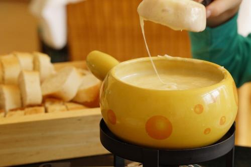 a person is pouring cheese into a pot of food at SOLUNA STAY I Seesicht I Luzern I Familienfreundlich I Self-check-in I Sunset I Ski I Free Parking in Küssnacht