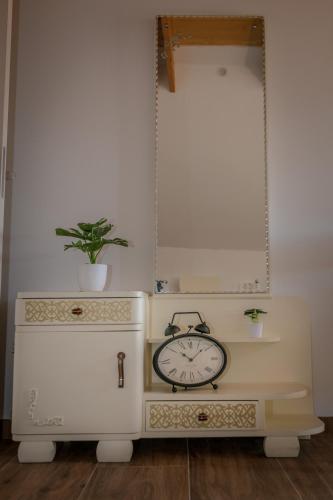a clock sitting on top of a dresser with a mirror at Apartments Šlosarjeva Hiša Nature & Tradition in Preddvor