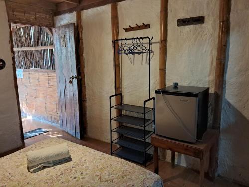 a room with a bed and a tv in it at Guacamayo Rooms & Bungalows in Máncora