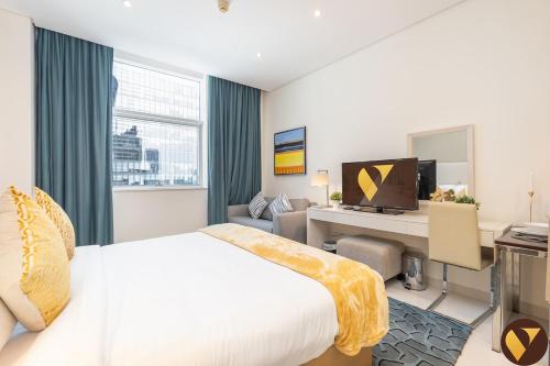 a hotel room with a bed and a desk with a computer at Vogue Vacation Homes, Business Bay Damac Cour Jardin close to Downtown, Burj Khalifa and Dubai Mall, Studio Apartment with City View, Access to all Amenities in Dubai