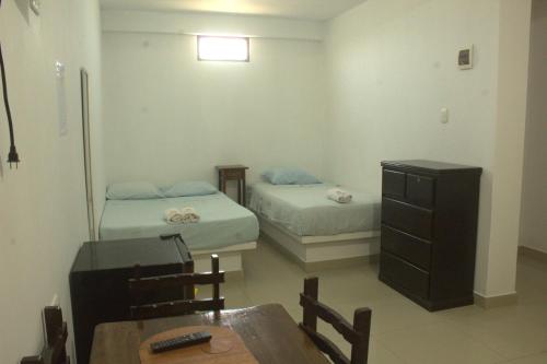 a room with two beds and a table and a desk at Bungalows Rupay Wasi in Los Órganos