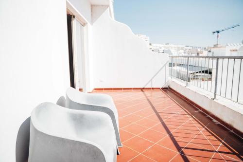 a balcony with two white chairs on a building at Stay Hotel Faro Centro in Faro