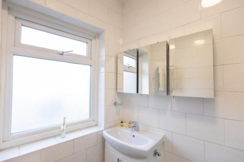 a white bathroom with a sink and a window at Large 4-Bedrooms Corporate Flat, Free Parking - Amazing Location in Leavesden Green