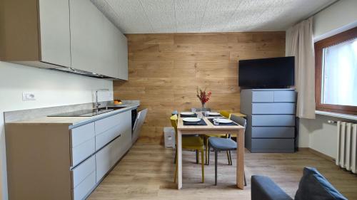 a kitchen with a table and a small kitchen with white cabinets at Hostdomus - Rainbow Apartment in Sestriere