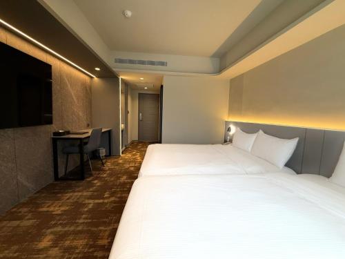 a hotel room with a large bed and a desk at Hub Hotel Ximen-inn Kunming in Taipei