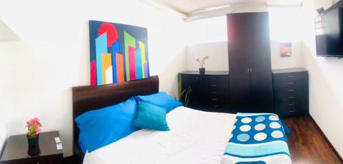 a bedroom with a bed with blue pillows at Habitaciones cerca a Universidad del Bosque in Bogotá