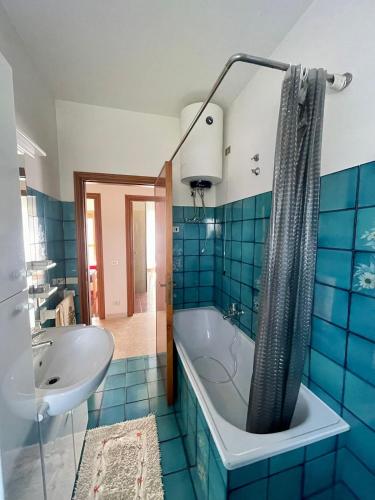a blue tiled bathroom with a tub and a sink at La porta del Gran Sasso in Montorio al Vomano