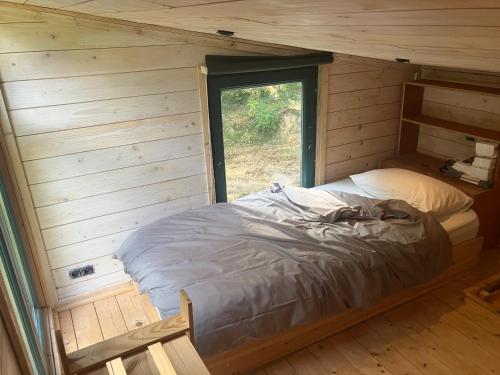 a bed in a wooden room with a window at Authentique, cosy et autonome en pleine nature in Clavier