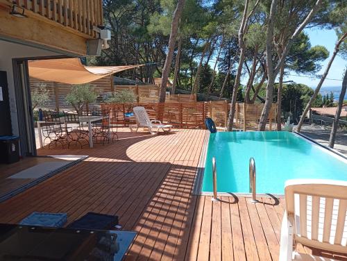 a swimming pool on a wooden deck with a table and chairs at Villa vu mer et étang de thau in Sète