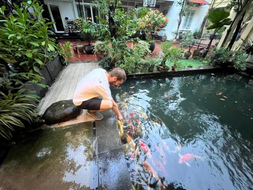 a man is looking at a koi in a pond at Lá house Hà Nội in Dong Anh