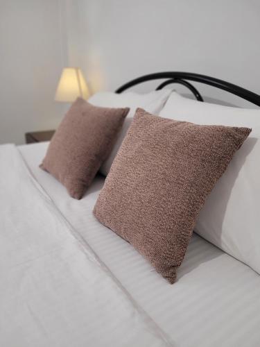 a bed with two brown pillows on it at Center River Apartment in Florina