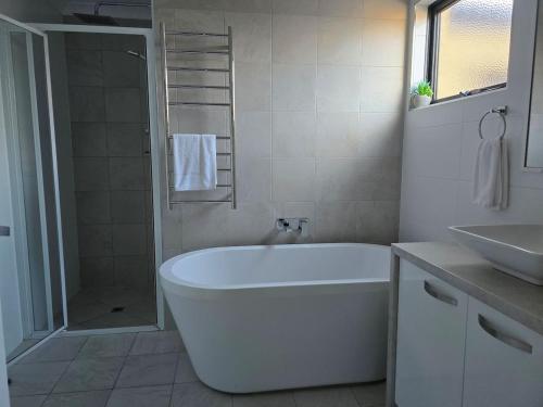a white bathroom with a tub and a sink at Esperance Ocean Escape in Esperance