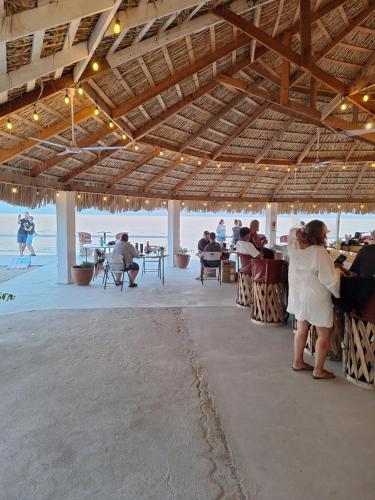 a group of people sitting at tables under a pavilion on the beach at #33 Bungalow Seaside Hotel & Victors RV Park in San Felipe