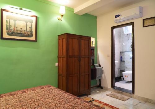 a bedroom with a green wall and a wooden cabinet at Diya Bed and Breakfast in New Delhi