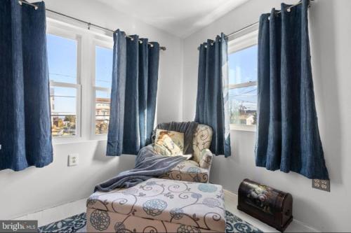 Un dormitorio con cortinas azules y una silla y una ventana. en Beach House Close to DE Turf, en Milford
