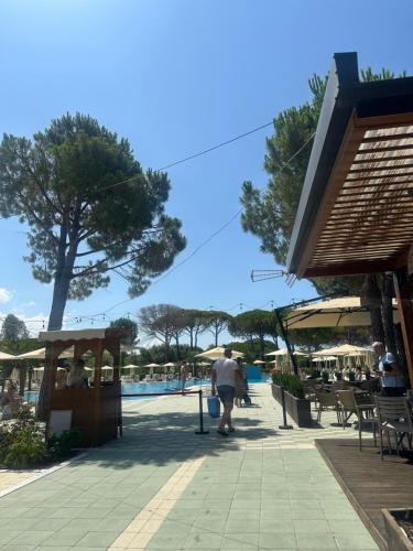 a man walking down a sidewalk next to a pool at Villa Amalia Perla Resort in Draçi