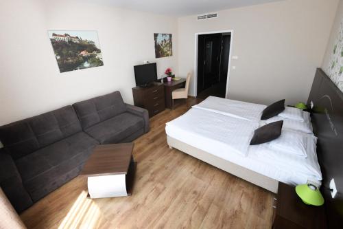 a bedroom with a bed and a couch at Ezüsthíd Hotel in Veszprém