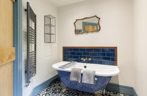 Un baño con una bañera azul y blanca y un espejo. en The Little Dairy Park Farm - Charming Countryside Retreat on the Isle of Wight, en Ryde