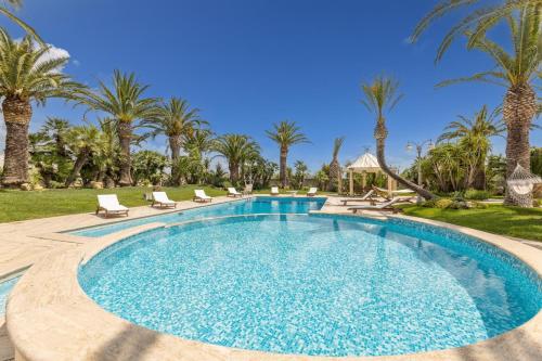 a swimming pool with palm trees in the background at Villa Oasi di Pace in Nardò