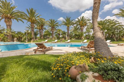 a resort with a pool with chairs and palm trees at Villa Oasi di Pace in Nardò