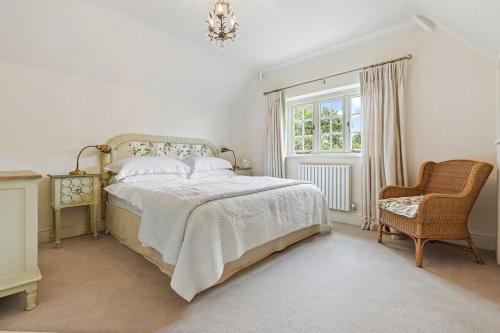 a bedroom with a bed and a chair and a window at Fieldview Cottage in Nettlebed