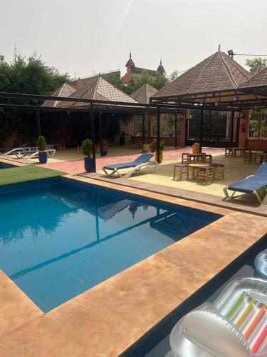 a swimming pool with chairs and umbrellas next to a house at FERME D'HOTES BARGHALi in Marrakech