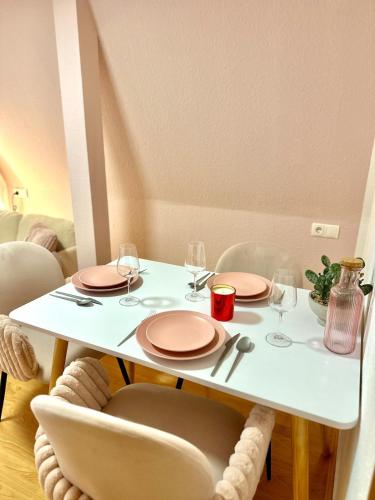 a white table with plates and wine glasses on it at Pink Sissi Hideaway mit Seeblick in Bregenz