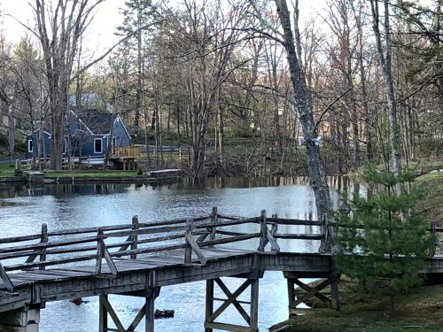 a wooden bridge over a body of water with a house at Cottage at Millpond Falls - A Romantic Escape in Warwick
