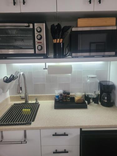 a kitchen counter with a sink and a microwave at Cozy Escape in Charlestown