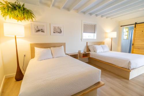 a bedroom with two beds with white sheets and a lamp at Driftwood Motel in Bay Saint Louis