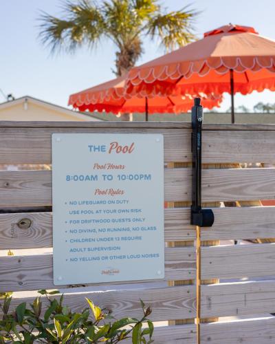 a sign on a fence with an umbrella at Driftwood Motel in Bay Saint Louis