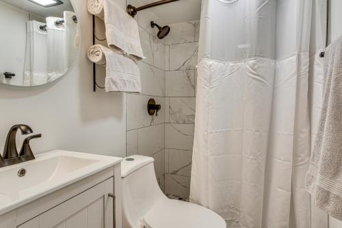a white bathroom with a toilet and a sink at 2 Mi to USC Campus Peaceful Apartment with Yard in West Columbia