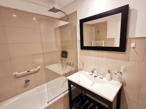 een badkamer met wastafel en douche met spiegel bij AC Suites XL in Puerto Madryn