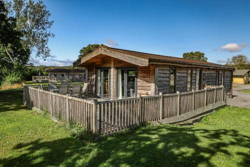 a wooden cabin with a fence in the grass at Oystercatcher Lodge Riverdale in Ripon