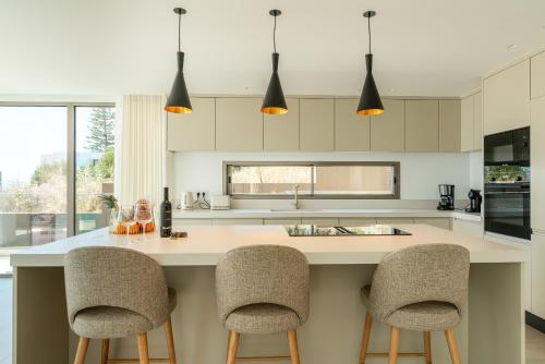 una cocina con una isla grande con 2 taburetes en Villa das Neves by AnaLodges, en Estreito da Calheta