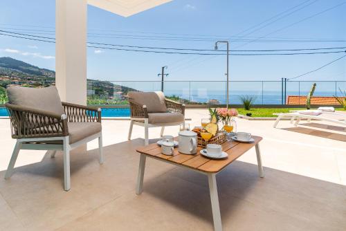Un patio con dos sillas y una mesa de café con vista. en Villa das Neves by AnaLodges, en Estreito da Calheta