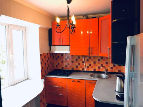 a kitchen with orange cabinets and a sink at Seven Apartments 66 in Vyshneve