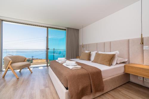 a bedroom with a large bed and a large window at Villa das Neves in Estreito da Calheta