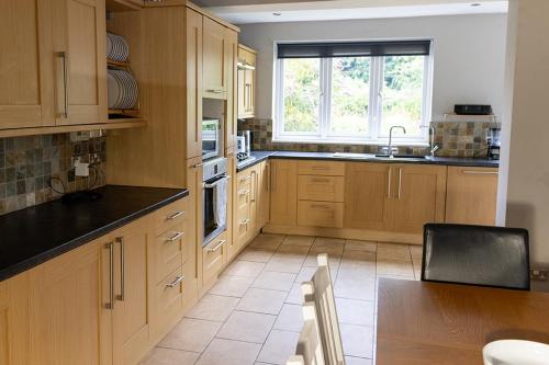 a kitchen with wooden cabinets and a table and a window at The Lodge - luxurious country stay with Hot tub, Games room and Gym in Canterbury
