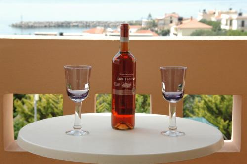 a bottle of wine sitting on a table with two glasses at Toulipa Rooms in Agia Ermioni